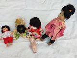 five dolls that are sitting on a bed together
