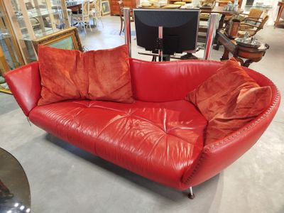 un canapé en cuir rouge avec des coussins, dans un magasin
