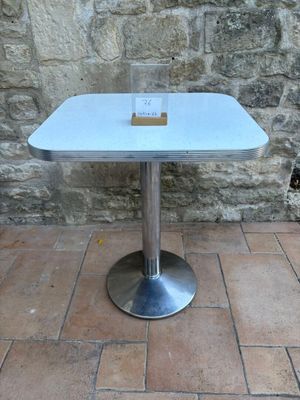 une petite table avec un plateau en verre, posée sur un sol en briques