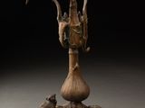 une sculpture en bronze représentant une tête de chèvre posée sur une souche d'arbre