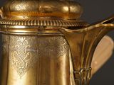 a gold coffee pot with a wooden spoon in it