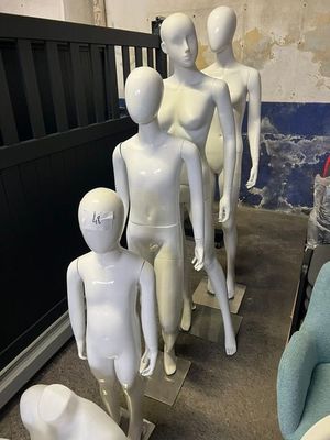 Plusieurs mannequins sont alignés dans une pièce où se trouve une chaise bleue