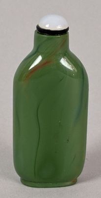 a green glass bottle with a white cap sitting on a table