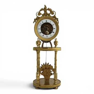une horloge en or posée sur un socle, accompagnée d'un panier de fleurs