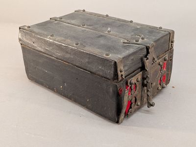 une vieille boîte en métal avec des poignées rouges sur un fond blanc