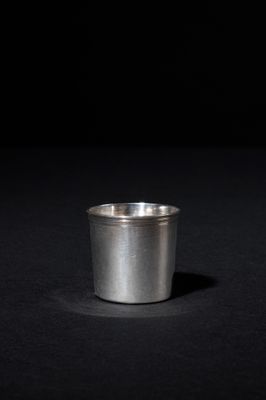 a small silver cup sitting on a black surface