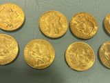 six gold sovereigns of various sizes and shapes on a table
