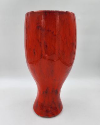 une image représentant un vase rouge posé sur une table blanche