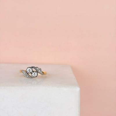 un gros plan d'une bague de fiançailles en diamant posée sur un bloc de marbre blanc