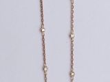 a close up of a necklace with a pink stone on it