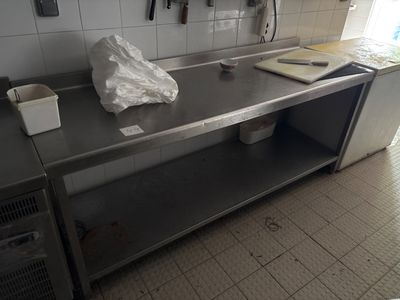 une cuisine équipée d'un grand plan de travail en inox et d'une poubelle