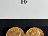 two gold sovereigns in a display case on a black surface