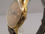 a gold wrist watch with a brown leather band
