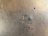 an antique silver plate with a metal handle on a table