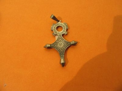 une croix argentée sur un fond orange avec une ombre