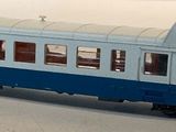 a blue and white train on the tracks on a white surface
