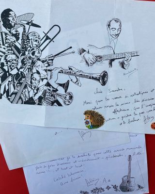 several drawings and letters are on a red surface with a pencil