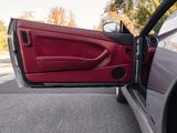 a red car with its door open sitting on the side of the road