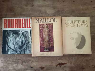 trois livres posés sur une table, avec une table en bois en arrière-plan
