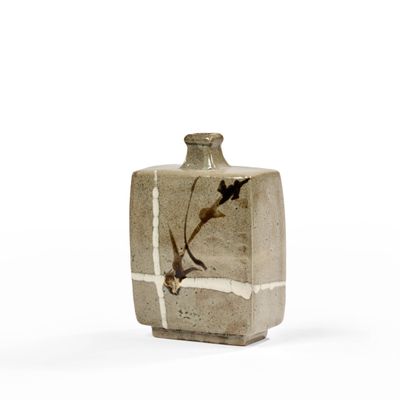 un petit vase avec un oiseau sur une surface blanche