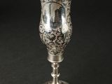 une coupe en argent ancienne posée sur une table noire
