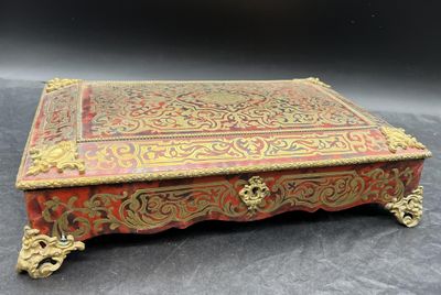 un coffret richement décoré, rouge et or, posé sur une table