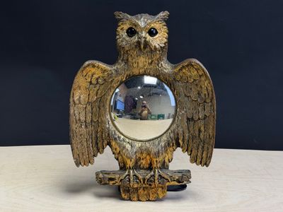 un hibou perché sur une table devant un miroir