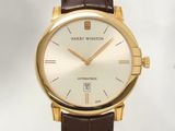 La montre est dorée et blanche, avec un bracelet en cuir marron.
