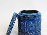 a blue cup with a lid sitting on a white surface