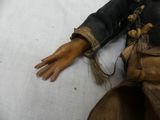 a doll that is laying on a bed with a hand on it