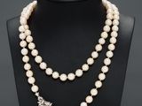 a white pearl necklace with a silver clasp on a mannequin