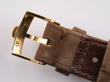 a brown belt with a gold buckle on a white surface