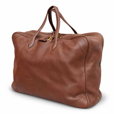 Le grand sac en cuir marron est posé sur une surface blanche.