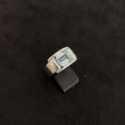 une image représentant une bague sertie d'une topaze bleue sur un fond noir