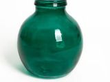 un vase vert posé sur une surface blanche