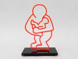orange neon sculpture of a man holding a baby on a black base