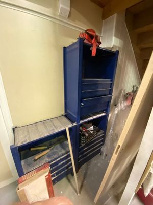 une photo d'une pièce avec une armoire bleue et une boîte à outils rouge