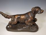 bronze statue of a dog on a rock on a white background