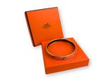 une boîte orange contenant un bracelet, posée sur une surface blanche