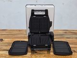 a close up of a waffle maker sitting on a wooden table