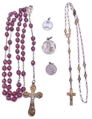 rosary, medal, and coin laying next to each other on a white surface