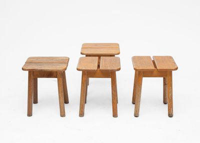three small wooden stools sitting next to each other on a white surface