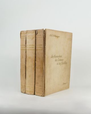 two old books sitting on top of each other on a white surface