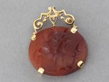 a close up of a gold plated pendant with a red stone