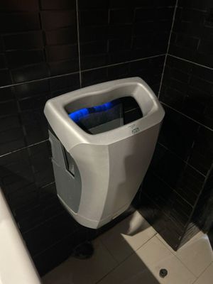 un urinoir situé dans un coin des toilettes, éclairé par une lumière bleue