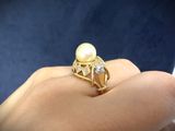 an image of a woman ' s hand holding a pearl and diamond ring