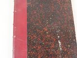 un livre à la couverture rouge posé sur une surface blanche
