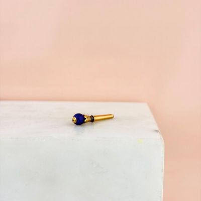 une broche de revers ornée d'une pierre bleue posée sur un bloc blanc