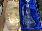 a glass vase in a box with a gold handle