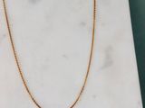 un collier à chaîne en or posé sur une dalle de marbre